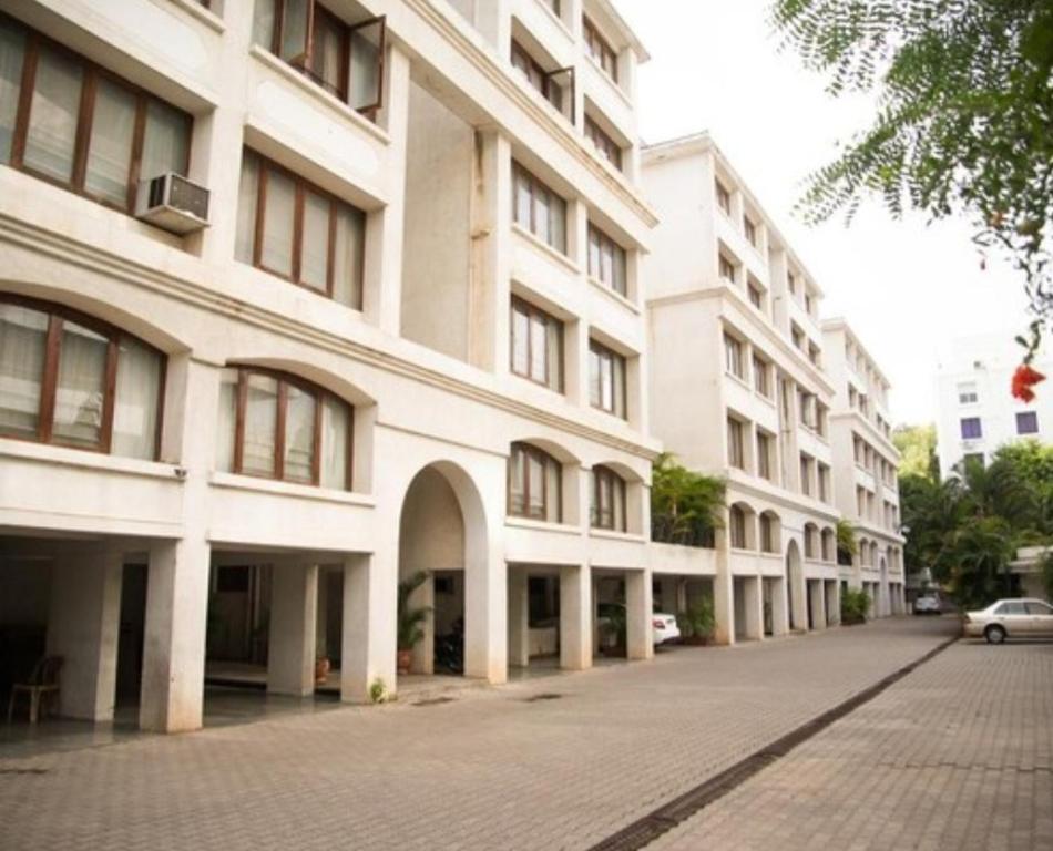 un grande edificio bianco con un'auto parcheggiata di fronte di Hermitage Residences Koregaon Park a Pune