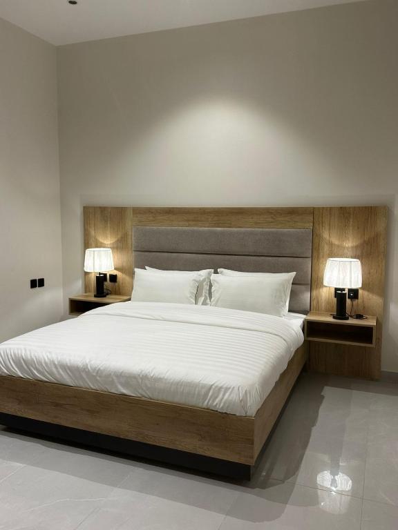a bedroom with a large bed with two lamps at W Hotel Apartment in Taif