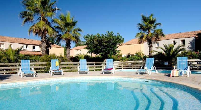 un groupe de chaises longues et une piscine dans l'établissement Bord De Mer Vendres plage, à Vendres-Plage