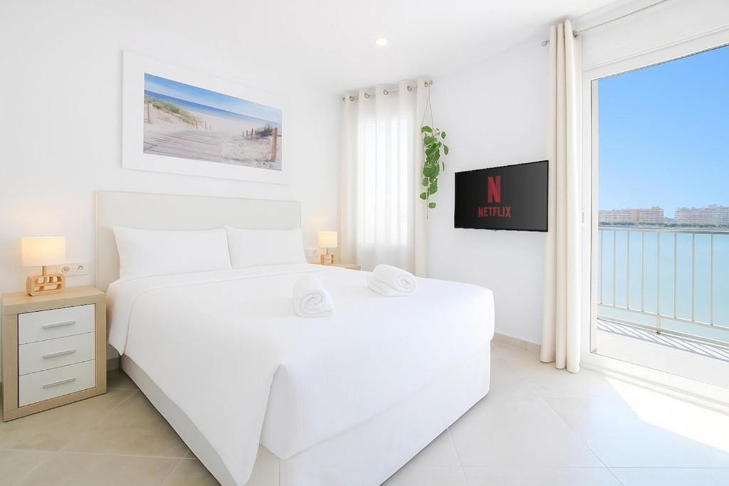 a white bedroom with a large white bed and a window at RiuRau Home - Studio 50 meters from the beach in Calpe