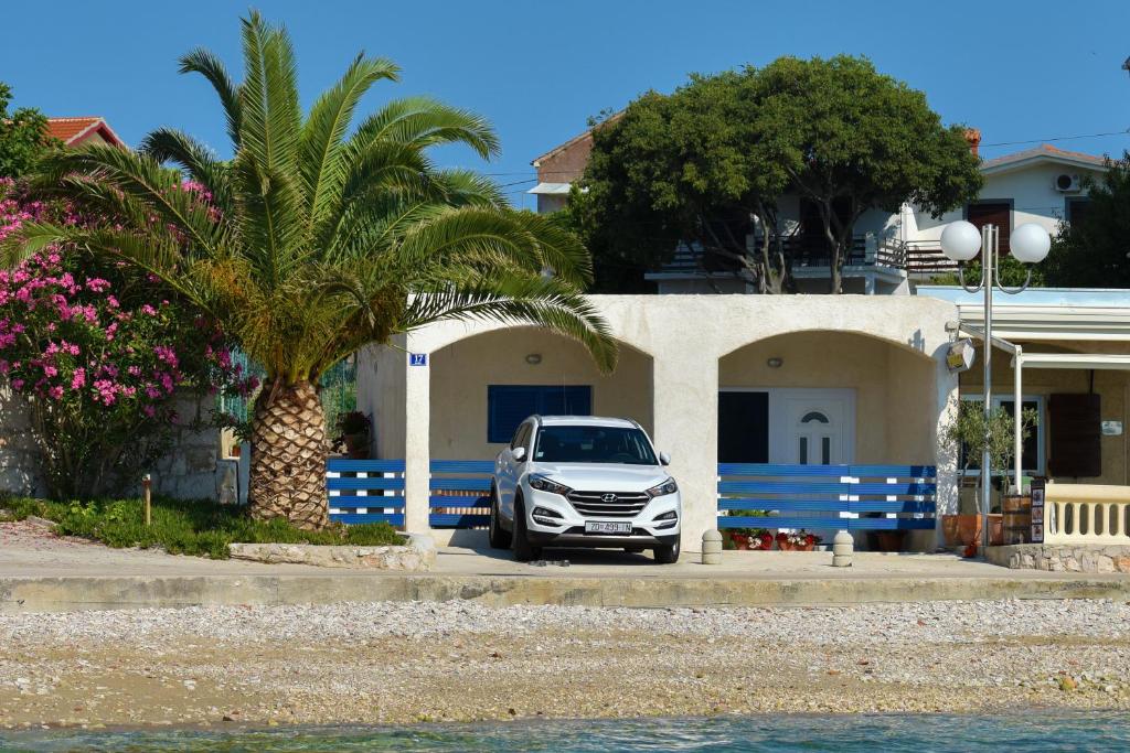 um carro estacionado em frente a uma casa com uma palmeira em Apartment Rita em Preko