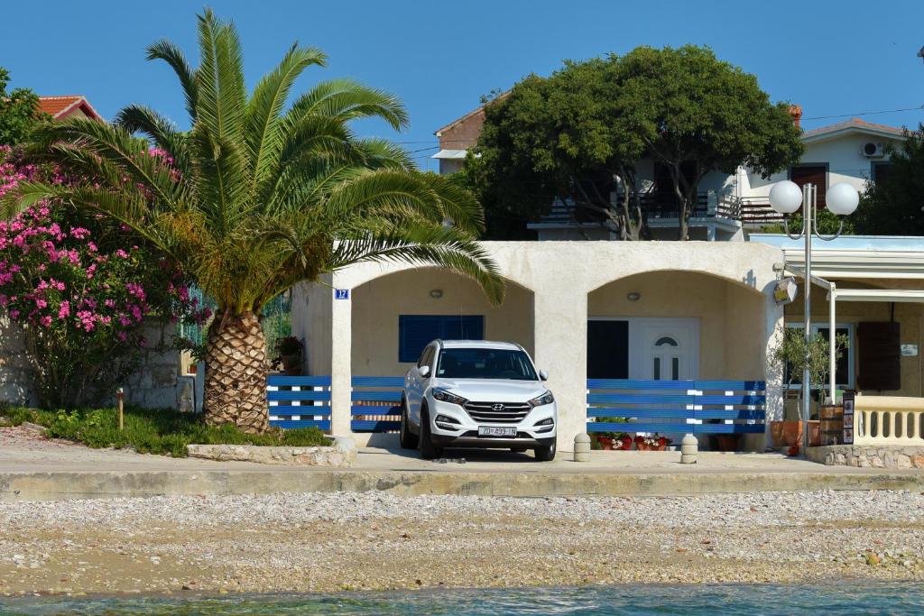 a car parked in front of a house with a palm tree at Apartment Rita in Preko