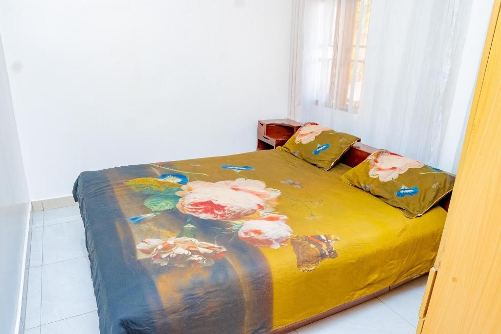 a bed with a yellow blanket with flowers on it at Casa tranquila in Kigali
