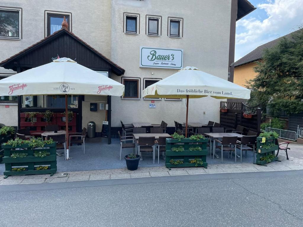 a restaurant with tables and umbrellas in front of a building at Bauer´s Pension-Restaurant-Catering in Großhabersdorf
