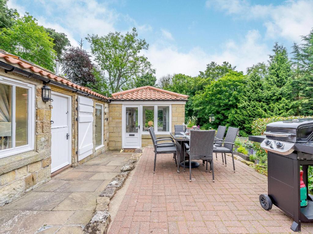 a patio with a table and chairs and a grill at Benchmark Cottage in Glaisdale