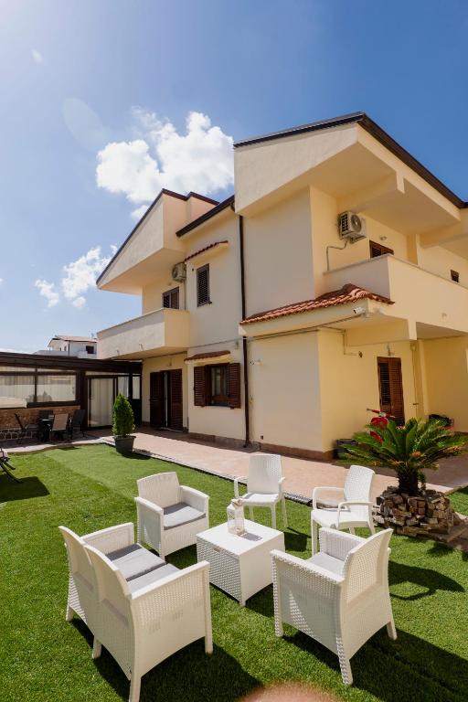a yard with white chairs and a house at Luna di Sale - Romantic Sea Rooms & Apartments in Reggio di Calabria