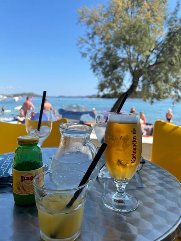 una mesa con dos vasos de cerveza y una botella en Bei Joschko, en Pakoštane