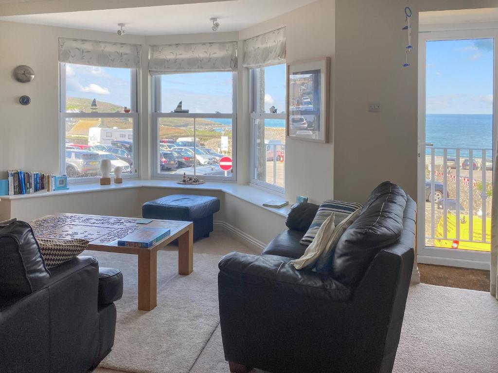 een woonkamer met banken, een tafel en ramen bij Ocean Breezes in St Ives