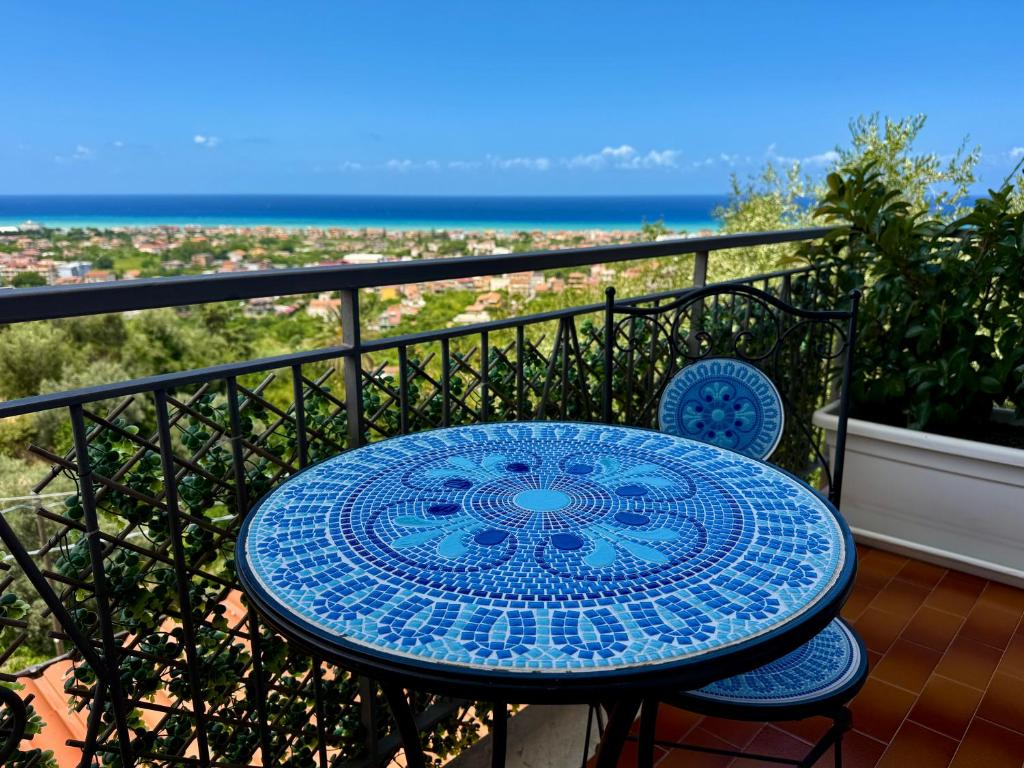 a blue table and chairs on a balcony with the ocean at B&B Il Tramonto in Capo dʼOrlando