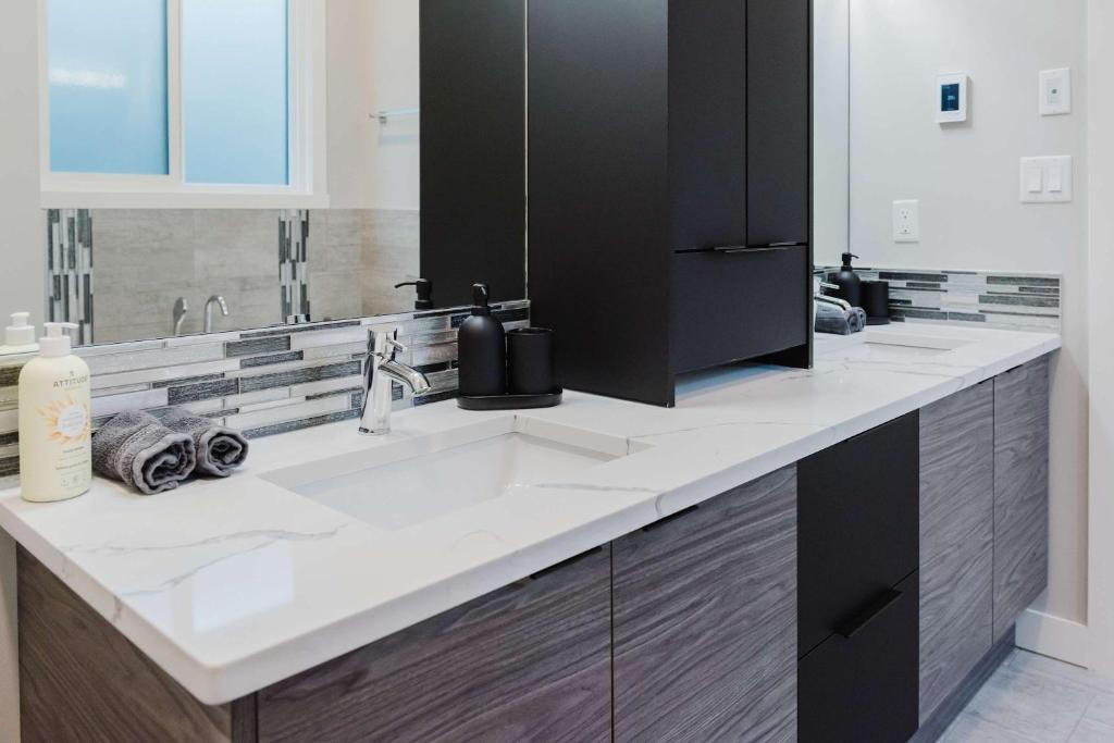 ein Badezimmer mit Waschbecken und großem Spiegel in der Unterkunft NordicSauna 3 Ensuite baths TheYellowDoorRetreat in Edmonton