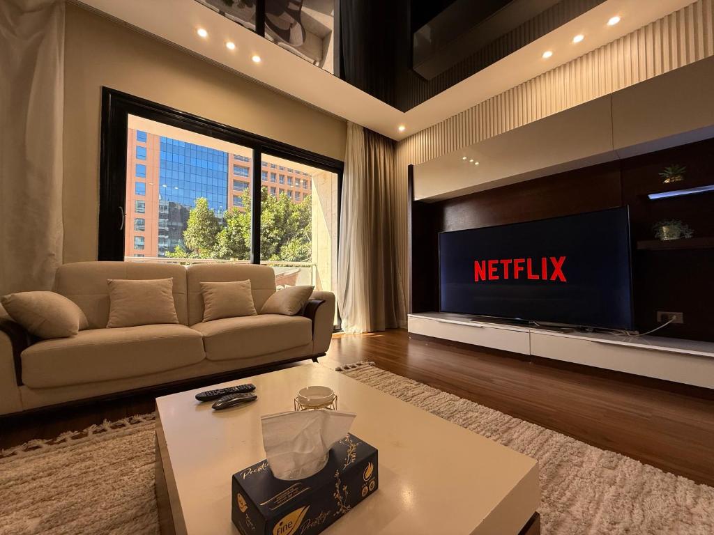uma sala de estar com um sofá e uma TV em Family Sparkling 2BR Facing CityStar em Cairo