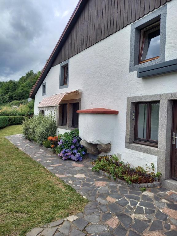 a white house with flowers in front of it at la Marcairie in La Bresse