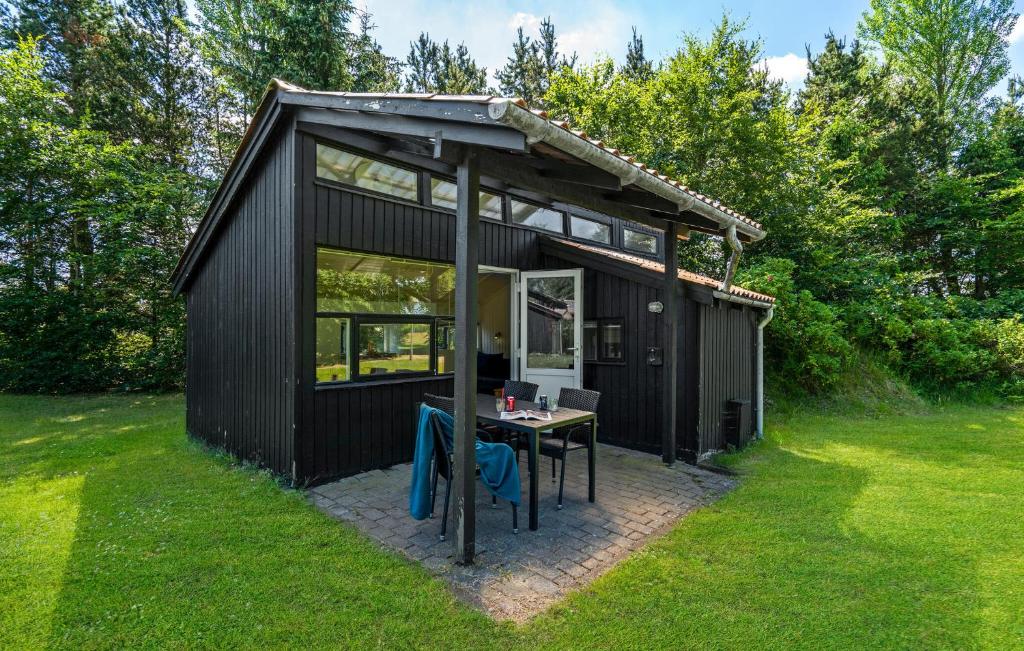 Un cobertizo negro con una mesa en el césped. en Stunning Home In Hampen With Wifi, en Hampen