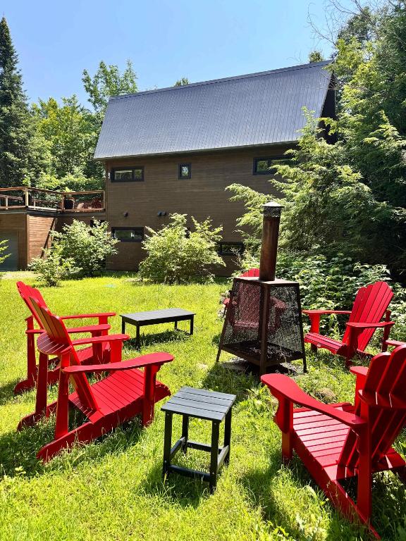 a group of red chairs and tables in the grass at Cottage 61 des Cervidés in Eastman