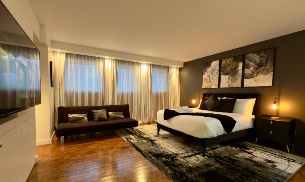 een slaapkamer met een bed, een bank en ramen bij Refuge Urbain Quebec - Loft Bonséjours in Québec