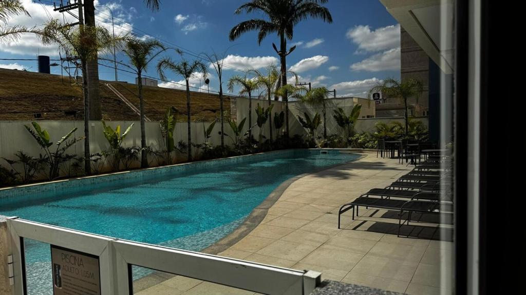 a swimming pool with chairs next to a building at New apartment in Bethaville, comfortable, Barueri in Barueri