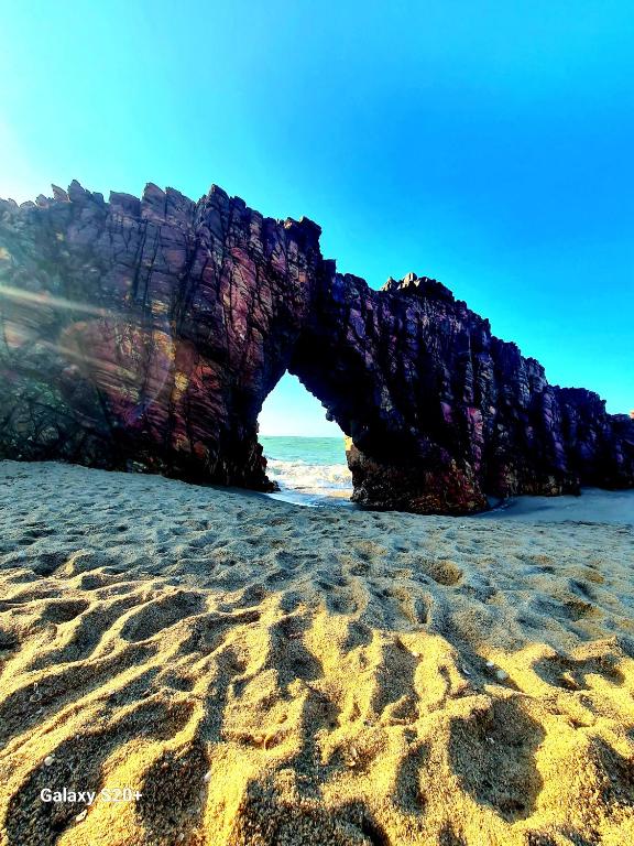 an arch in a rock formation on a beach at Refúgio do Preá - 700 Metros da Praia in Prea