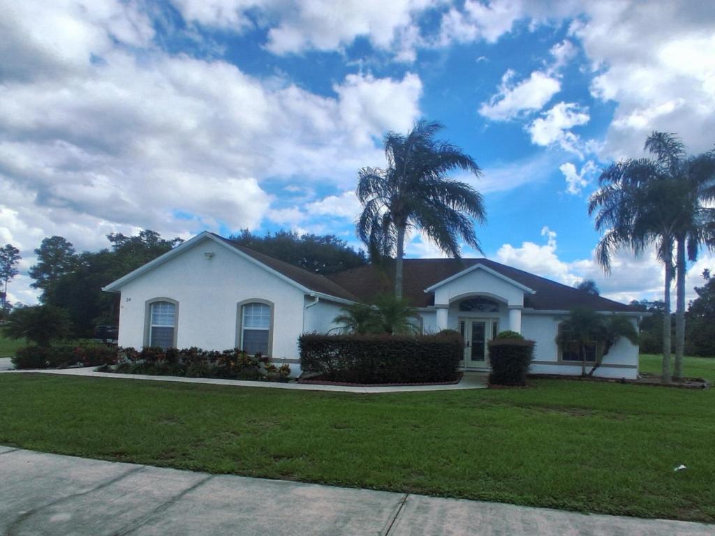 a white house with palm trees in front of it at Suite privada en orlando kissimmee con piscina privada in Kissimmee