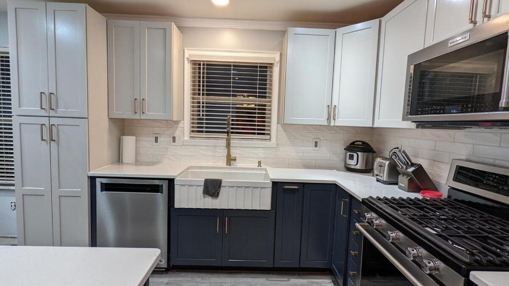 a kitchen with white cabinets and a sink and a stove at CulDeSec Home 4BR 3 Half Baths Sleeps 7 Jacuzzi tub in Columbus