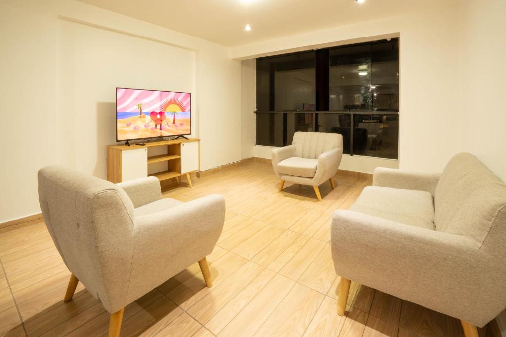 a living room with two chairs and a flat screen tv at Departamento para 14 personas Cusco in Cusco