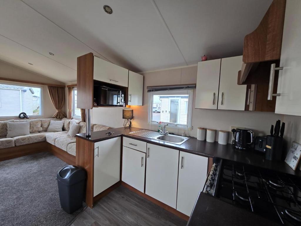 a kitchen with white cabinets and a living room at Superb 8 Berth Caravan At St Osyth Beach, Essex Ref 28001G in Jaywick Sands