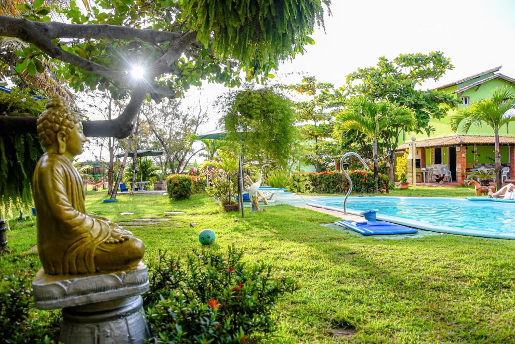 Un jardín con una estatua de Buda junto a una piscina. en Vila dos Ventos - RedeVilla, en Estância