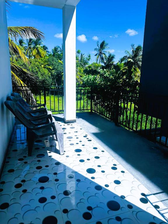 a patio with two chairs and a fence and trees at Seven Crest Hotel Anuradhapura in Anuradhapura