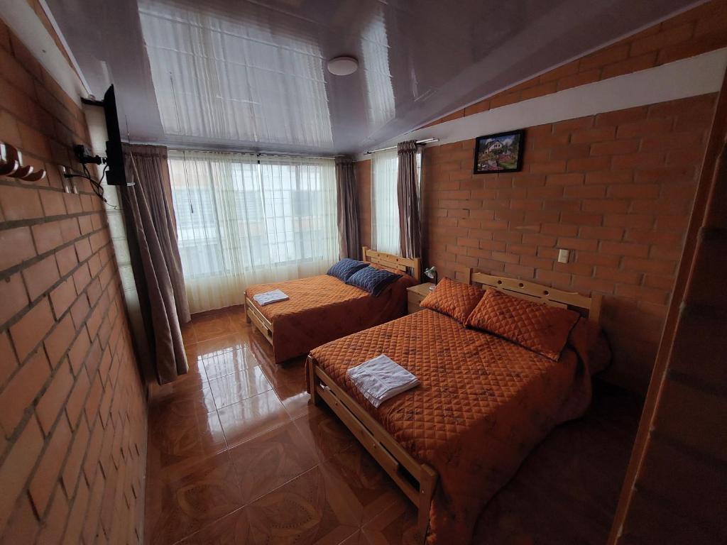 a bedroom with two beds and a brick wall at Casa Vacacional Paipa in Paipa