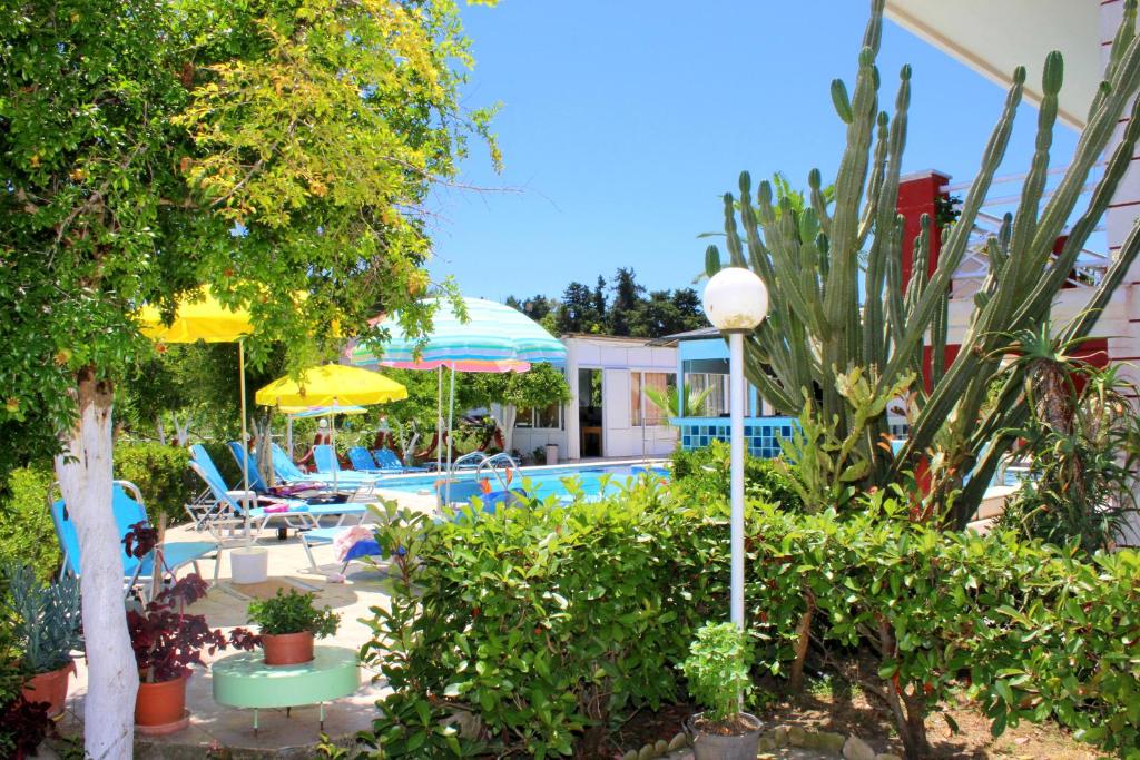 a pool with chairs and umbrellas in a yard at Crystal in Kavos