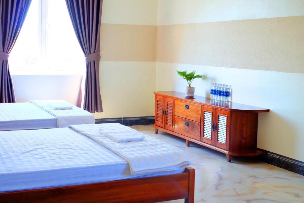 ホーチャムにあるMotel Thuỷ Lộc Hồ Tràmのベッドルーム1室(ベッド2台、木製ドレッサー付)