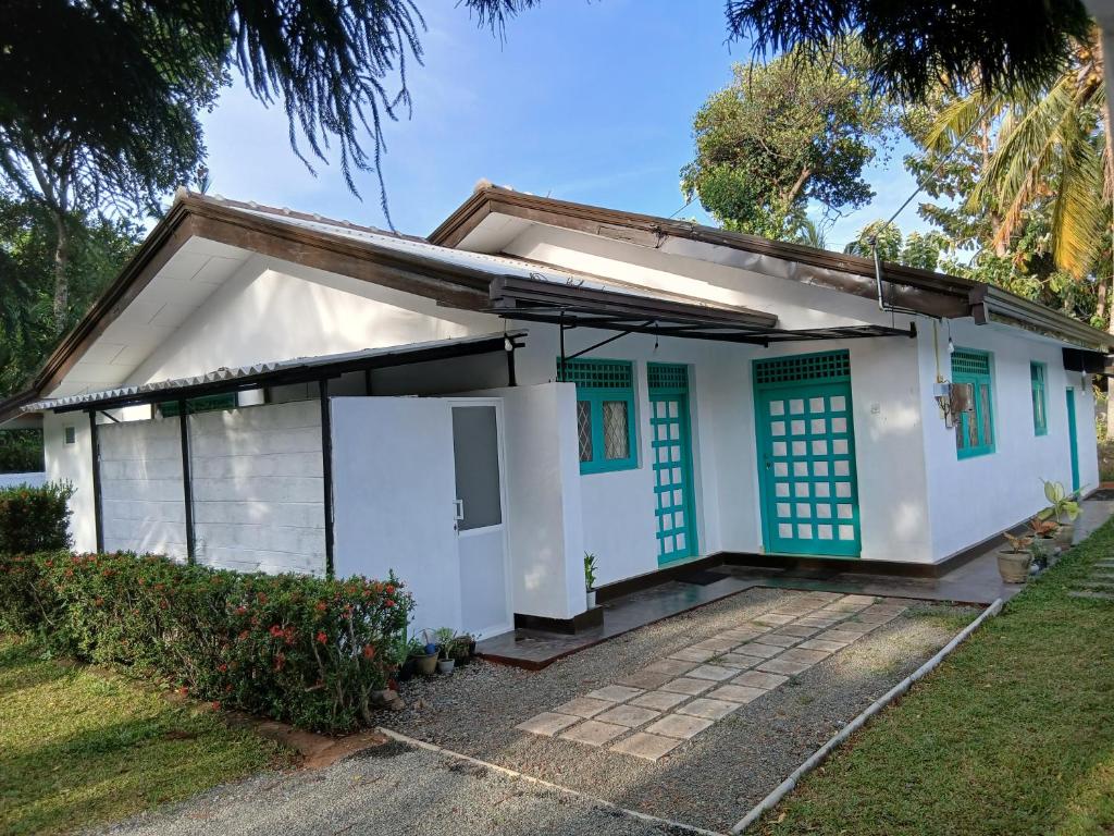 a small white house with blue doors at Villa Coleus in Tangalle