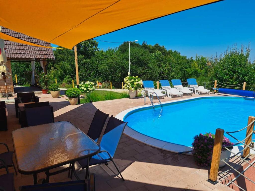 a swimming pool with chairs and a table and an umbrella at Koliba La Perla in Banja Luka