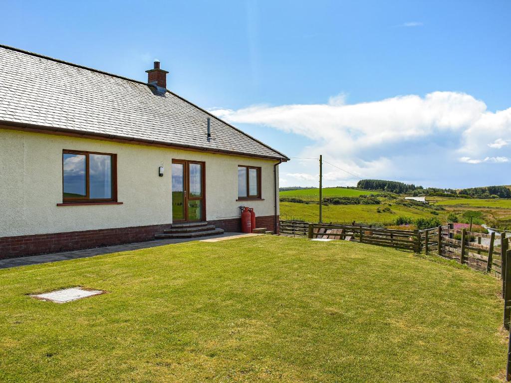 una casa con un patio de hierba delante de ella en Little Glengyre Farm, en Kirkcolm