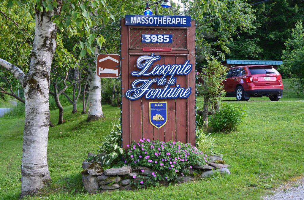 a sign sitting in the grass next to some flowers at Lecomte De La Fontaine in North Hatley