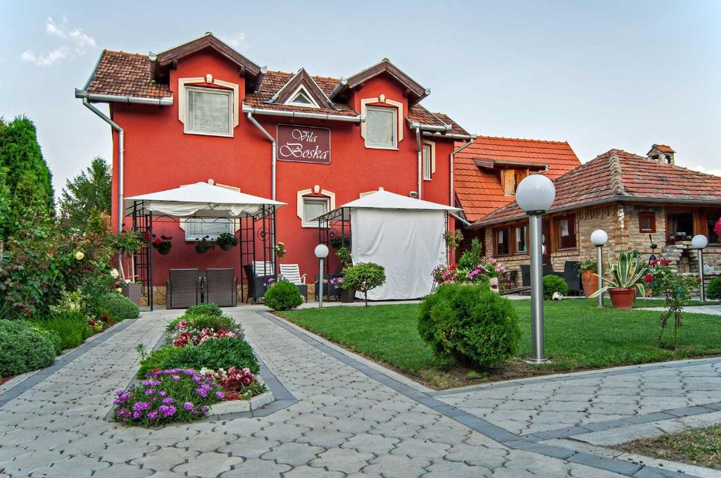 a red building with flowers in front of it at Vila Boska Palic in Palić
