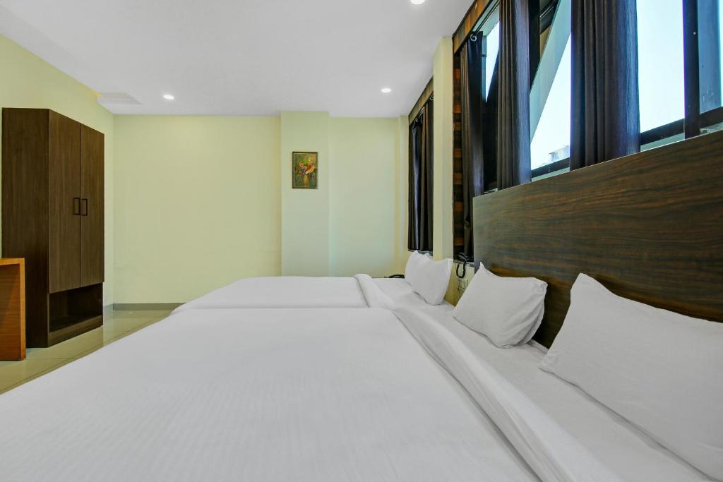 a large white bed in a room with windows at Hotel O Kinsfolk Inn in Ghaziabad