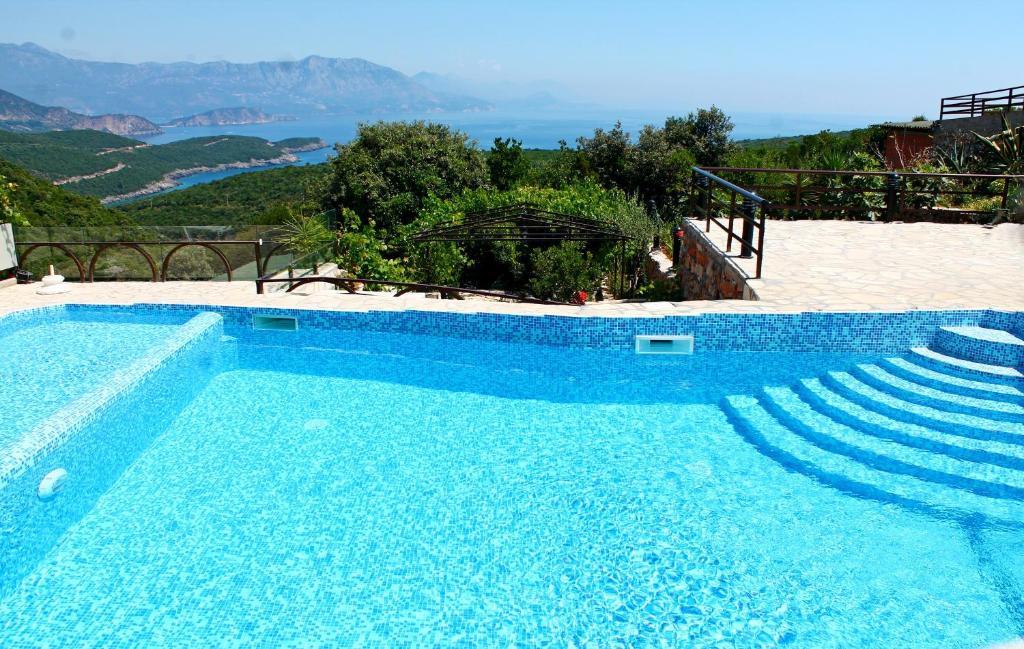 a blue swimming pool with a view of the ocean at Apartments Villa Milna 1 in Budva