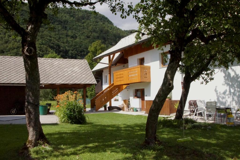 ein Haus mit einer Treppe in einem Hof mit Bäumen in der Unterkunft Apartments Markež in Bohinj