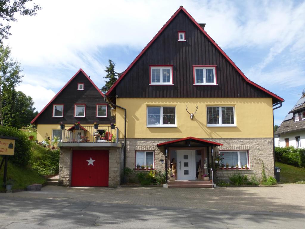 a yellow and black house with a red garage at Gästehaus HarzGlück in Braunlage