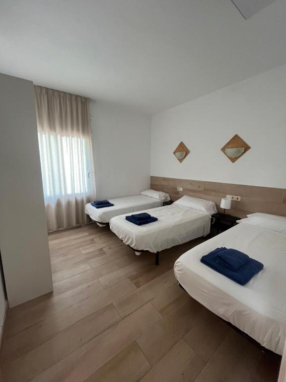 Una habitación de hotel con tres camas y una ventana. en Hostal Casa Torrent, en Canet de Mar