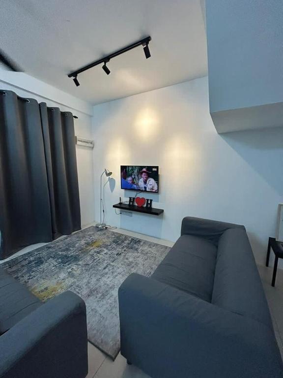 a living room with a couch and a tv on a wall at MH meru homestay in Chemor
