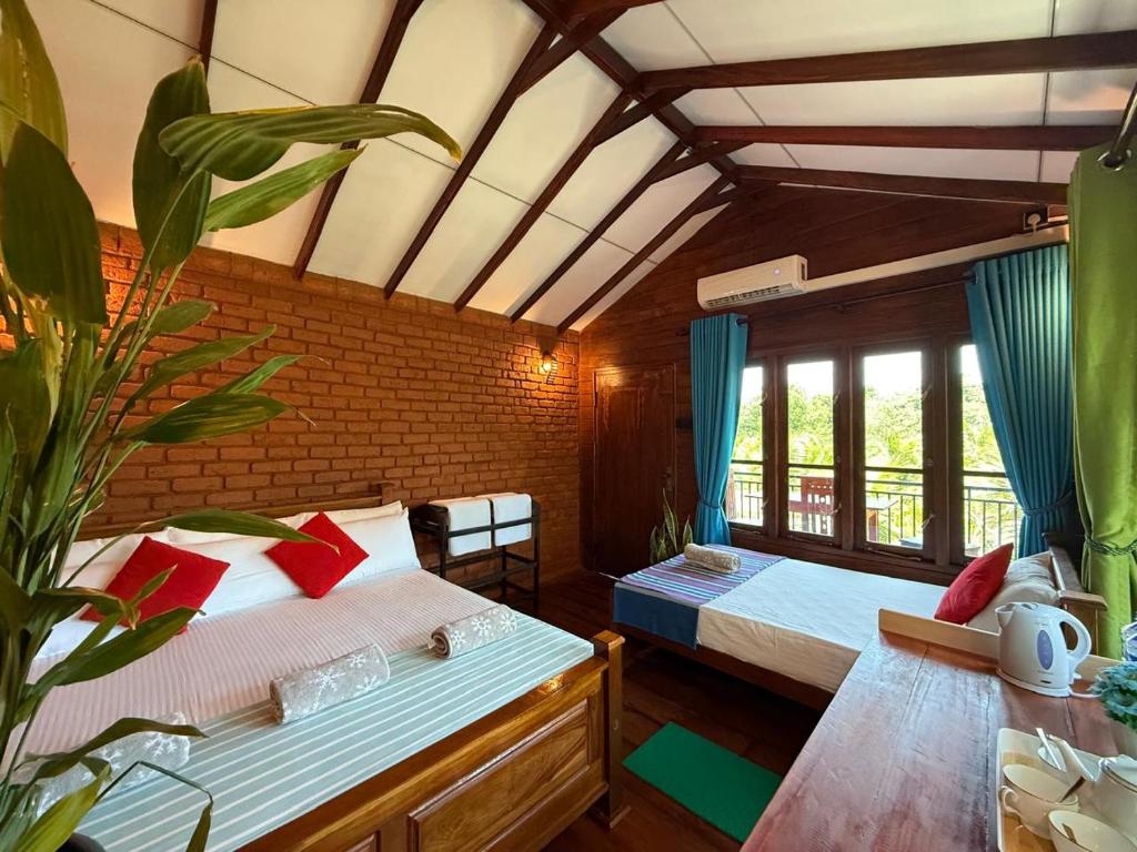 a bedroom with two beds and a table with a plant at Tree Top View Tree House in Sigiriya