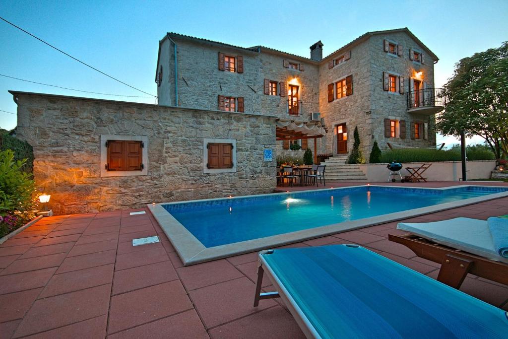 a house with a swimming pool in front of a building at Villa Angela e Giovanni in Vižinada