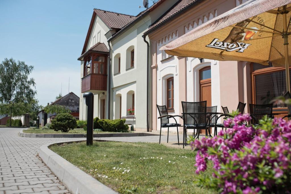 um pátio com cadeiras, um guarda-sol e flores em Penzion Nad Oborou em Hradec Králové