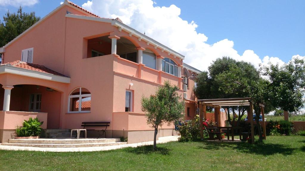 ein rosa Haus mit einem Garten davor in der Unterkunft Apartments Beba in Privlaka