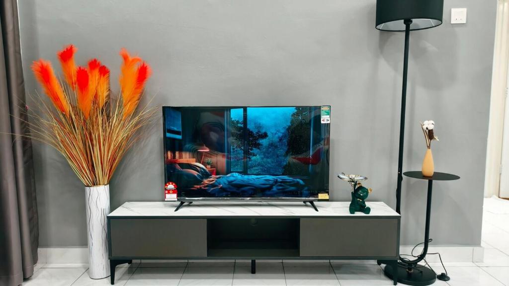 a living room with a tv and a vase with orange feathers at Event Hubs - Axiata Arena, Stadium Bukit Jalil in Kuala Lumpur