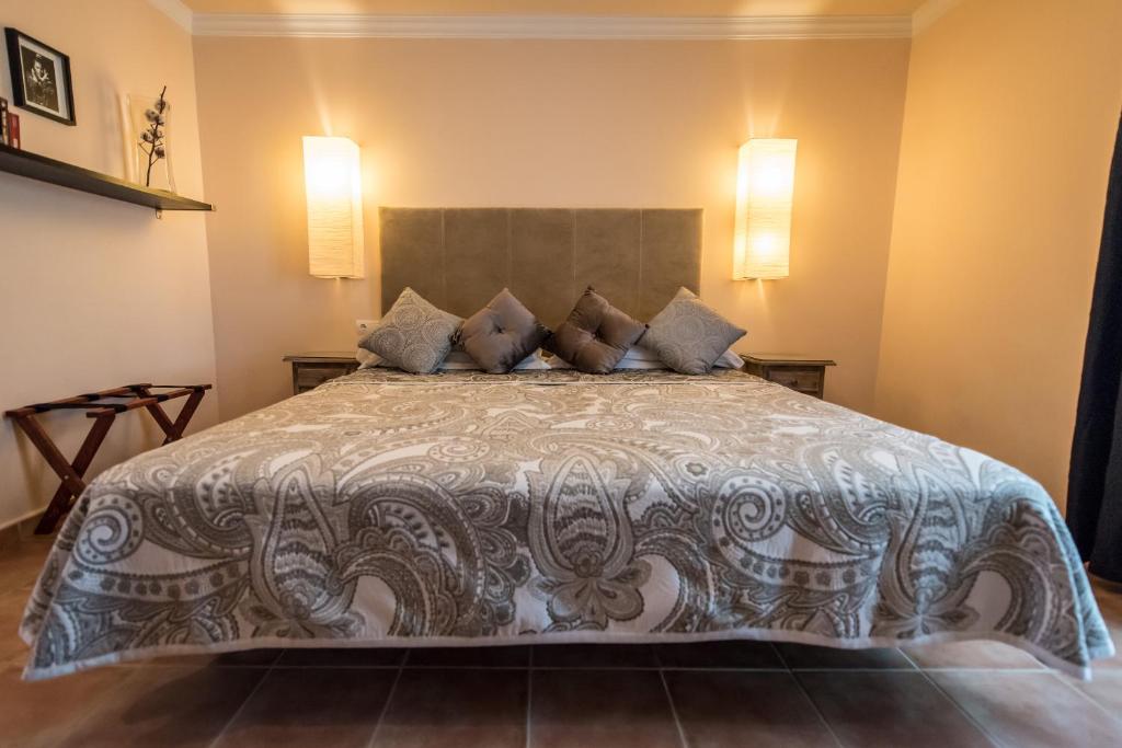 a large bed in a bedroom with two lights on the wall at Al Lago in Zahara de la Sierra