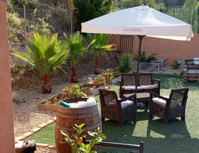 a patio with a table and chairs and an umbrella at Casa para fines de semana cuevas del turche buñol in Buñol