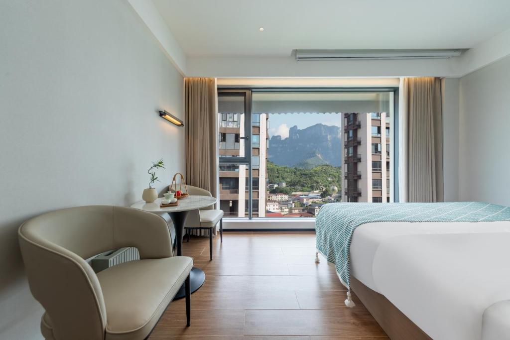a hotel room with a bed and a chair and a window at 张家界天门山索道站 Xiaduo B&B - 夏朵民宿-Planning-book Tickets Service in advance-Free Luggage in Wangjiazhai