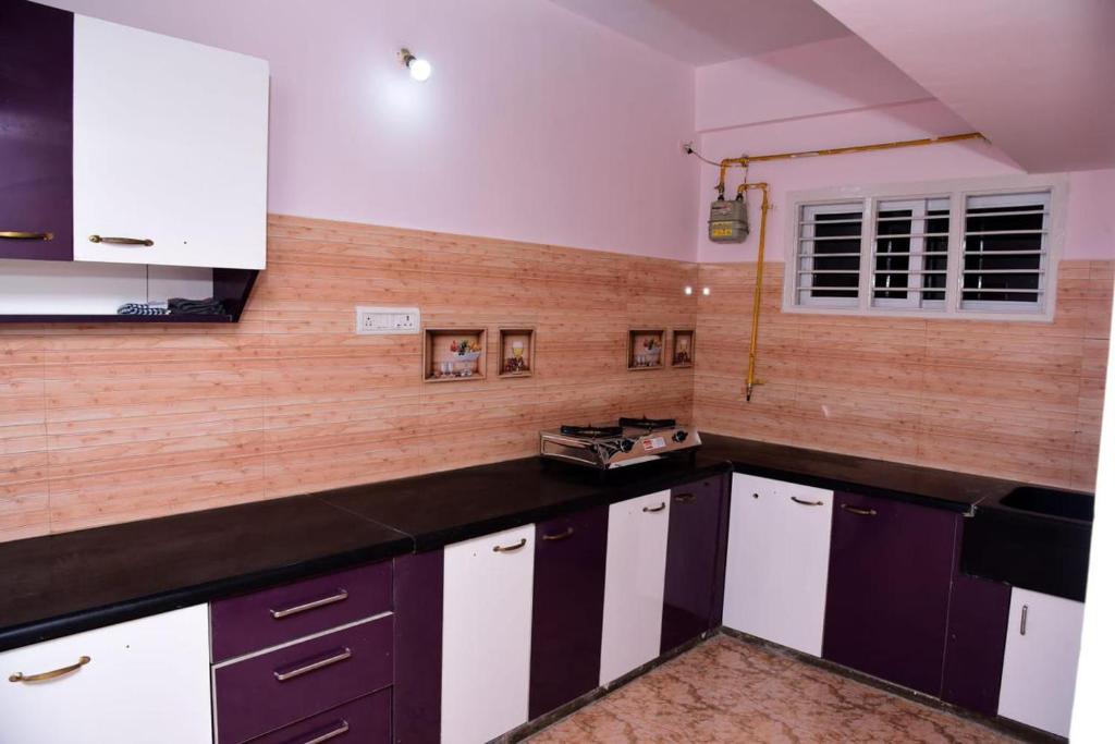 a kitchen with black and white cabinets and a window at Urbanstay Service Appartment in Bengaluru